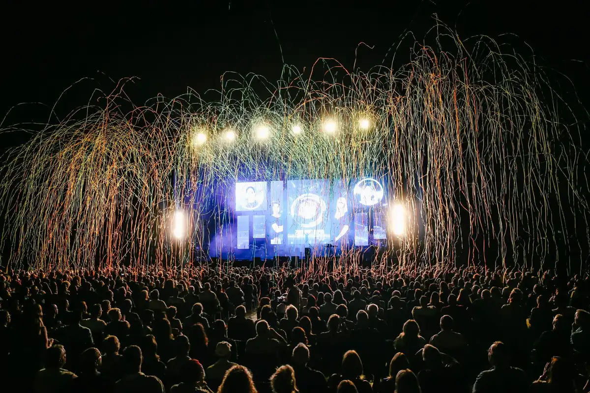 Crowd silhouettes under stadium lights with banners removed, distant and anonymous, fans in motion blur