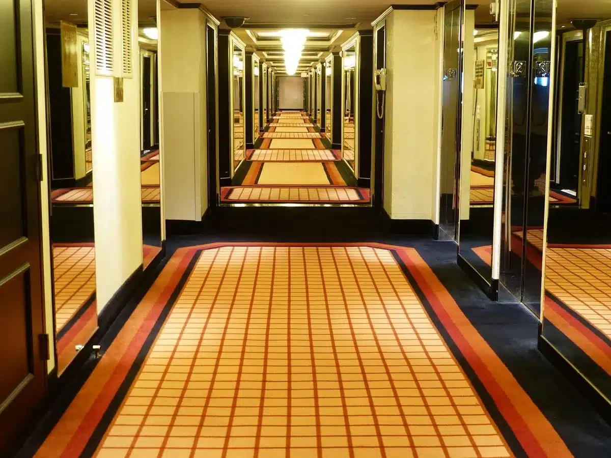 Empty hospital corridor with an anonymous wheelchair at the end of the hall, soft daylight through high windows