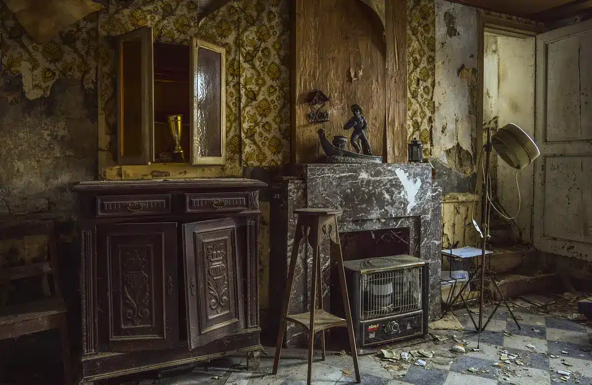 Sala vazia com móveis desgastados e paredes descascadas