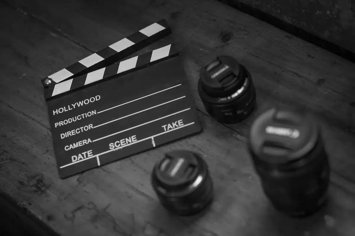 Close-up of a generic production slate and unbranded camera equipment on set, crew silhouettes out of focus — evokes increased local production activity