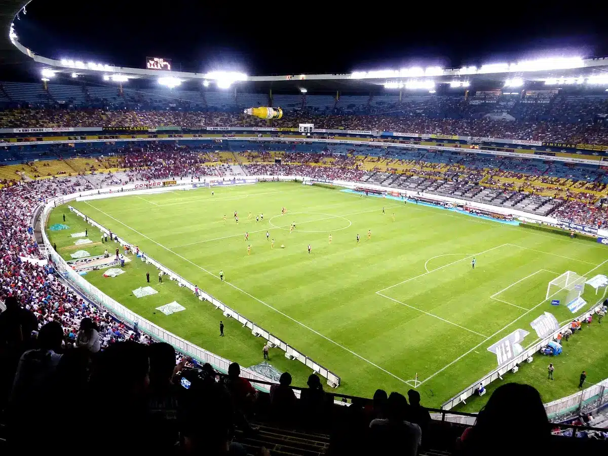 Empty stadium stand with anonymous fans silhouettes under daytime floodlights
