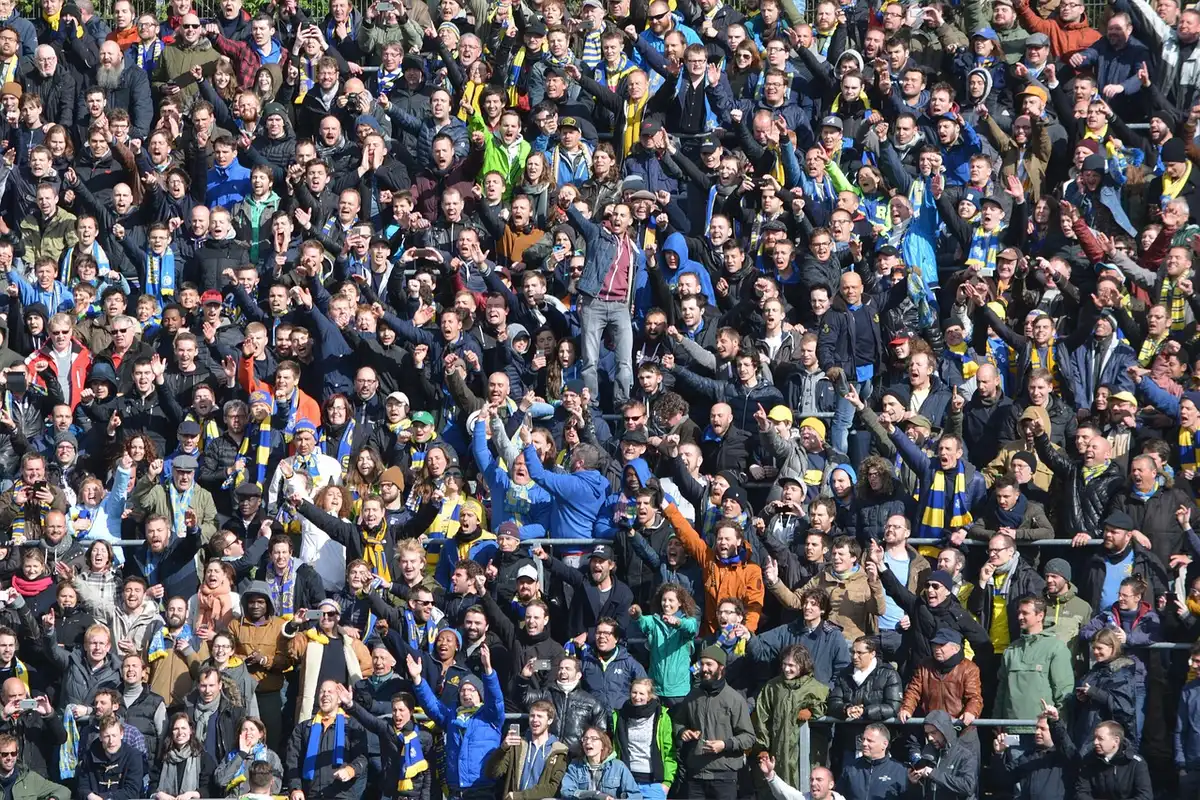 Anonymous crowd in white and sky-blue scarves waving, motion blur, no identifiable faces