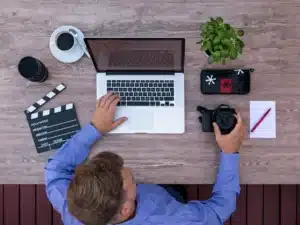 Mãos anônimas manuseando um rolo de filme e um claquete em uma sala de edição