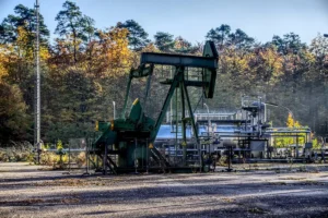 Miniatura de barril de petróleo e relatórios sobre uma mesa de escritório, mão apontando para mapa