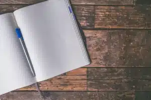 Caderno e caneta sobre mesa com corredor desfocado ao fundo