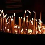 Corredor de igreja vazio com velas acesas e crucifixo em silhueta