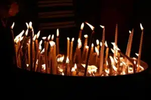 Corredor de igreja vazio com velas acesas e crucifixo em silhueta