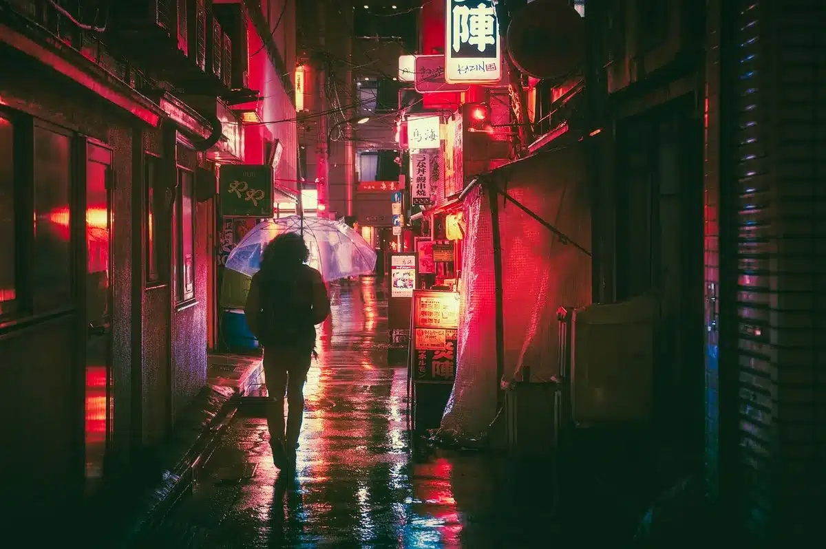 Lantern-lit village street with a lone closed door and scattered festival banners, suggesting aftermath tension and abandoned celebration
