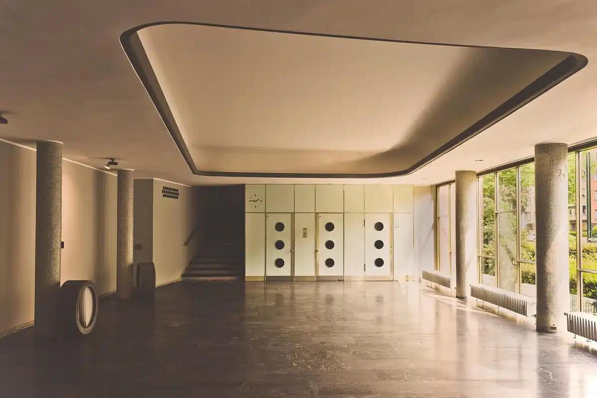 Empty cinema foyer with a single glowing ticket kiosk and a poster stand showing an abstract alien silhouette
