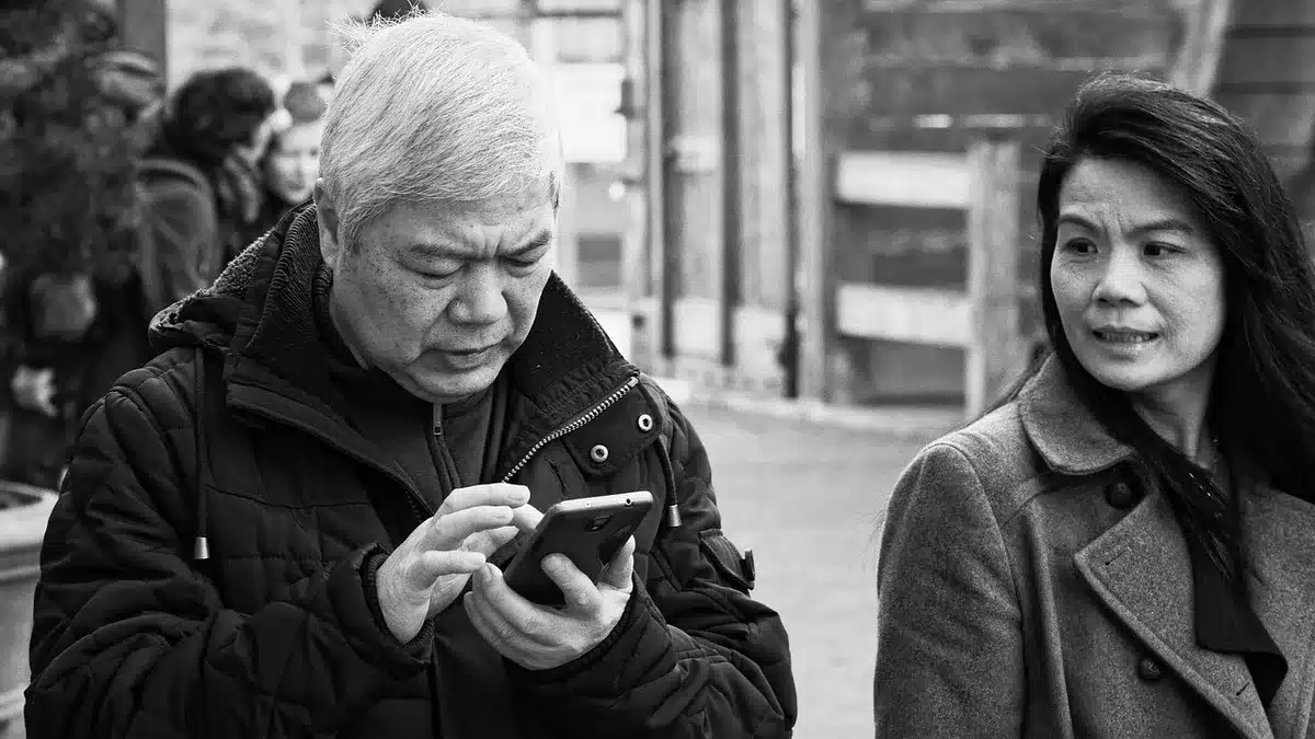 Crowd of anonymous smartphone users in soft focus, hands holding phones up in a social-event atmosphere, no identifiable faces or logos